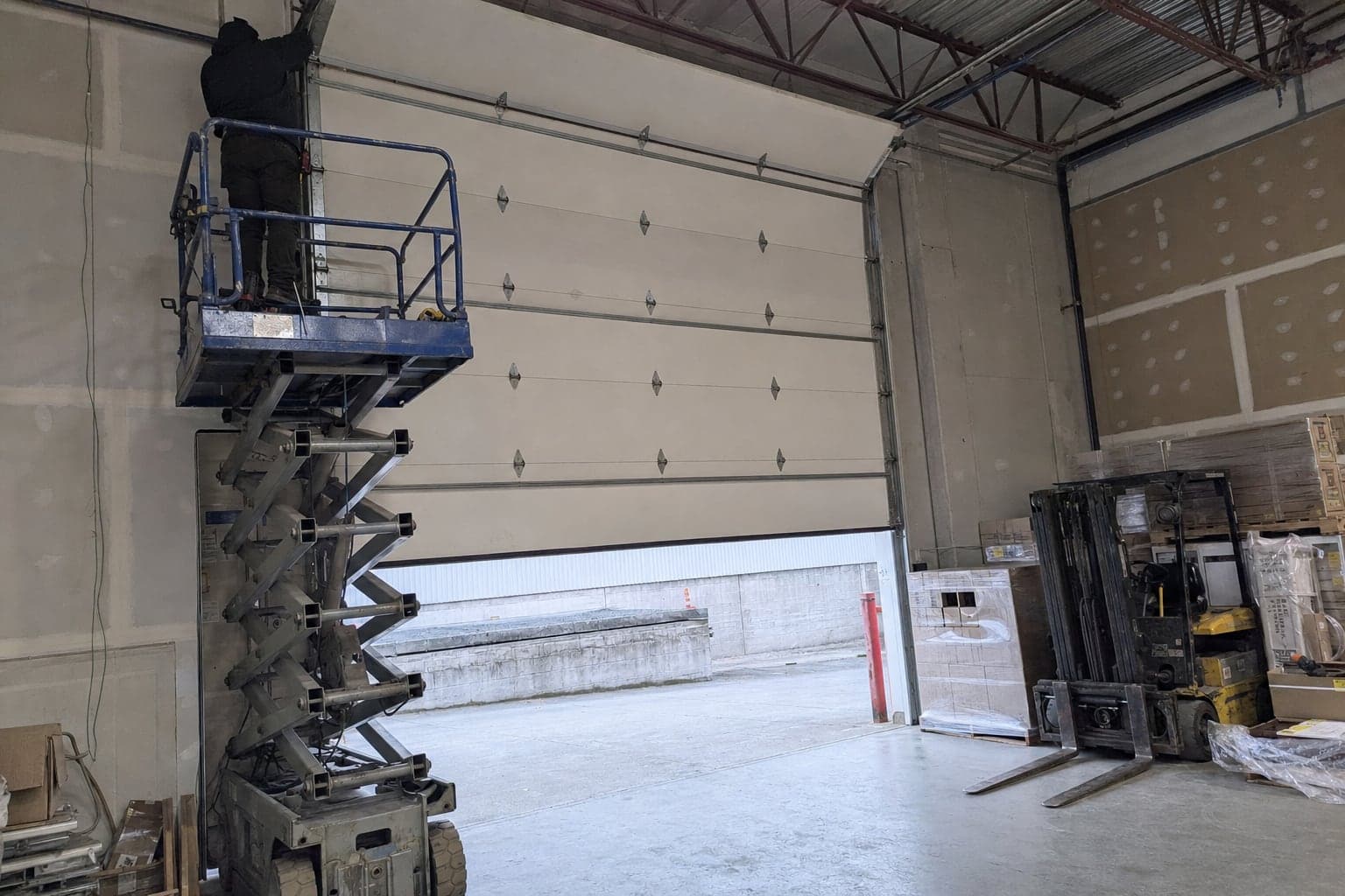 Technician on a lift at a warehouse overhead door