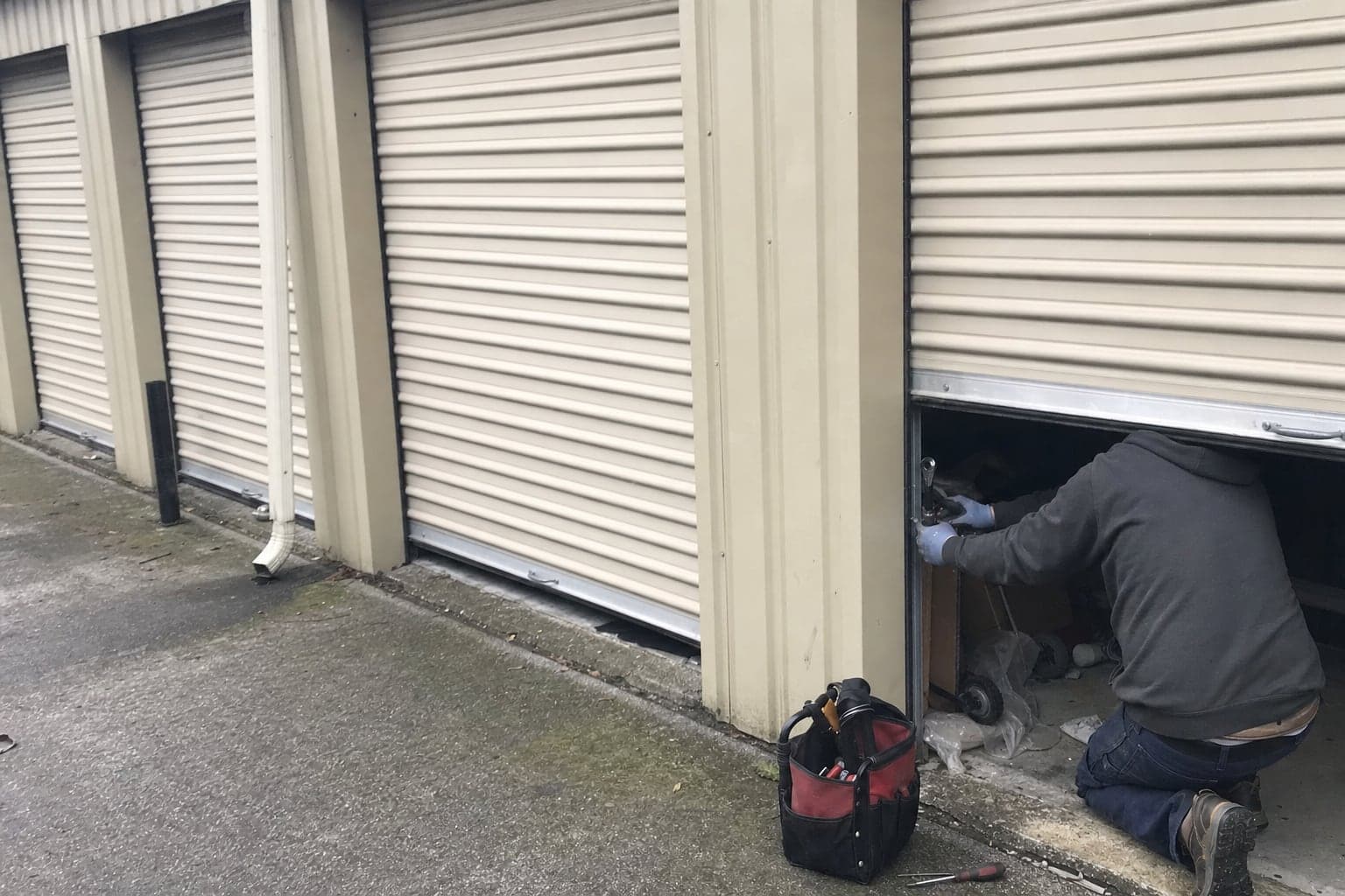 Working on the guide of a rolling steel door at a storage unit